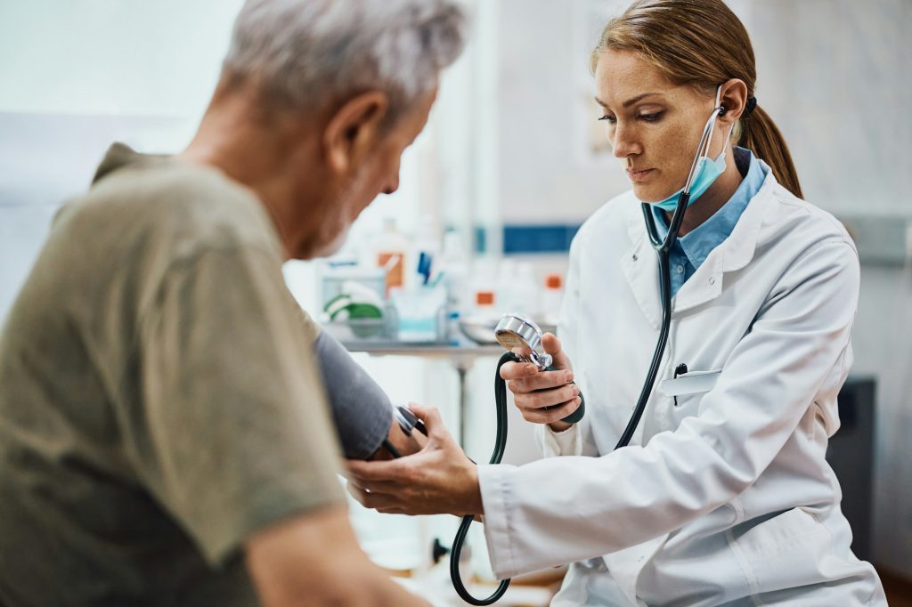 Female doctor doctor measuring senior man's blood pressure at medical clinic.