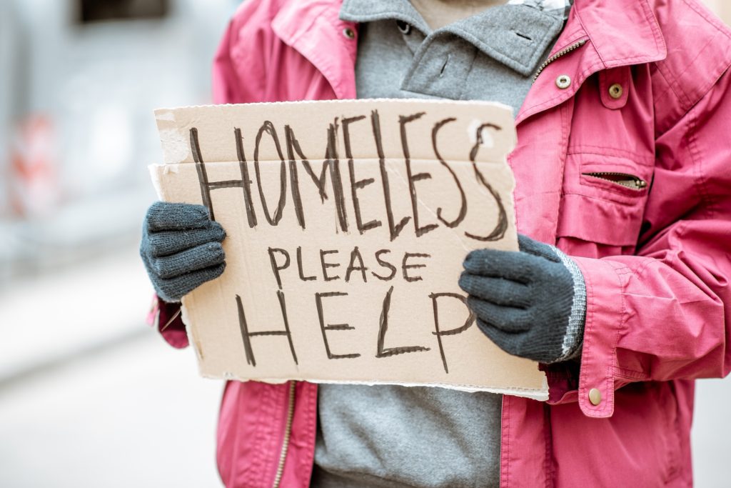 Homeless beggar with cardboard outdoors